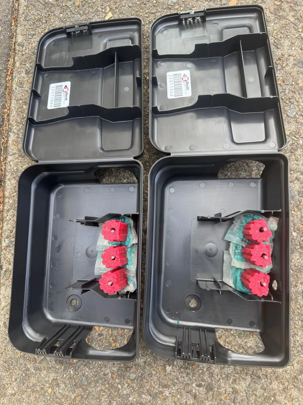 Two locked rodent bait stations with fresh bait blocks placed around a property
